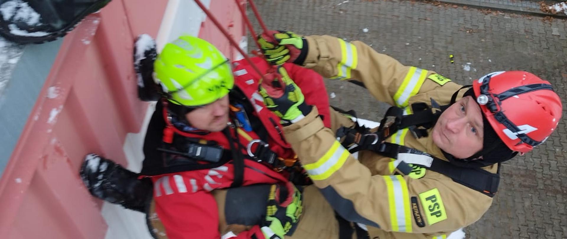 Strażacy ćwiczą ewakuacyjne techniki linowe.