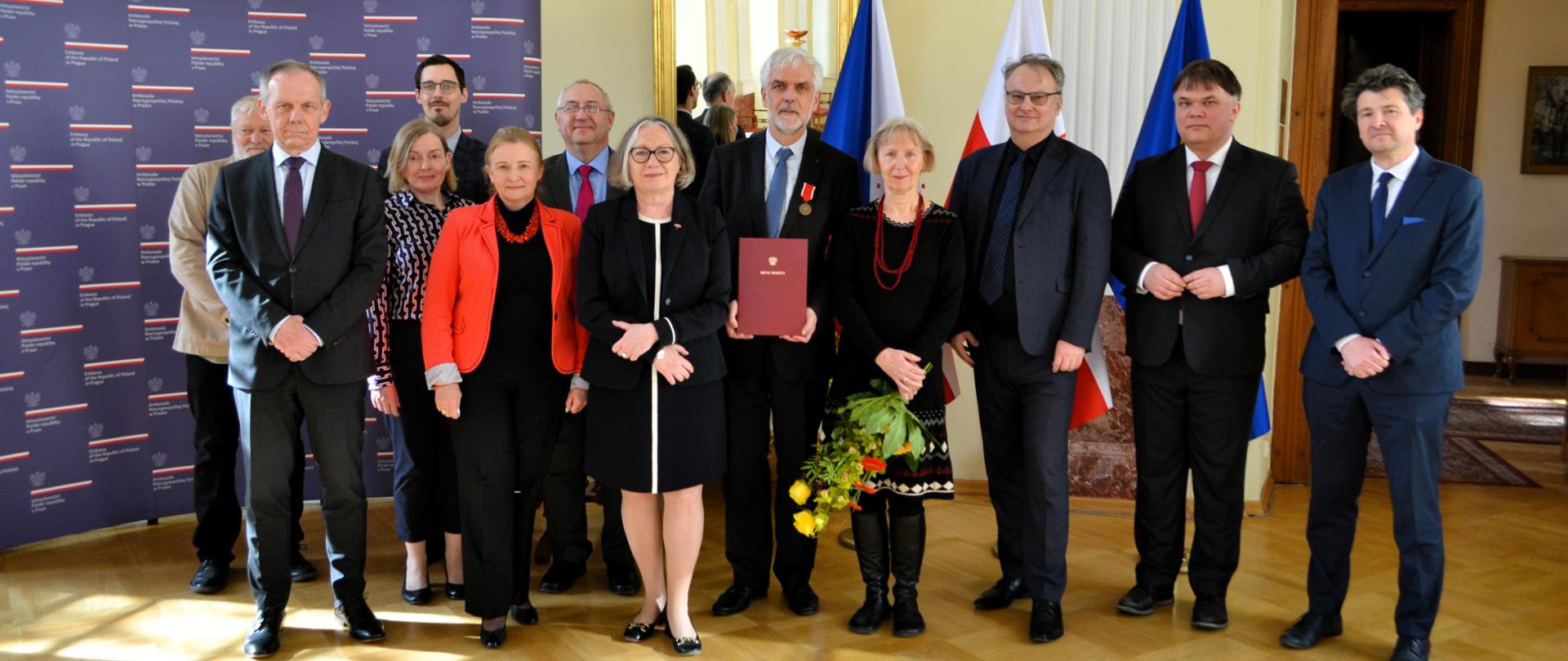 Společná fotografie. Dvanáct osob. Uprostřed w osvědčením vyznamenaný.