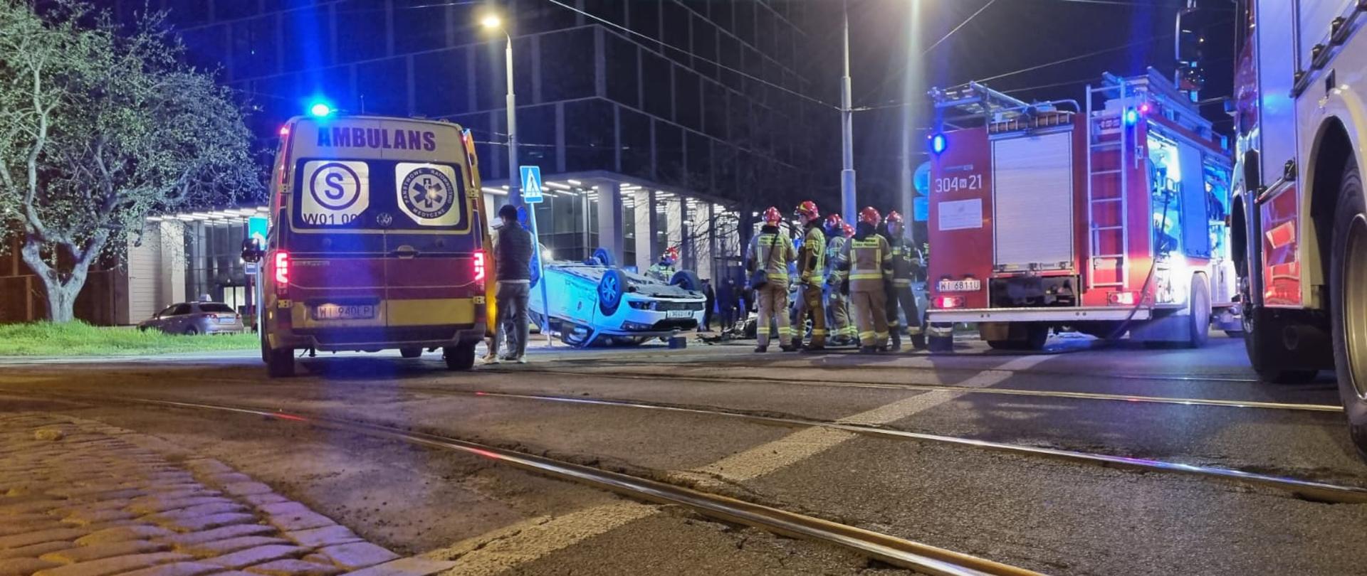 Służby ratownicze i samochód na dachu.