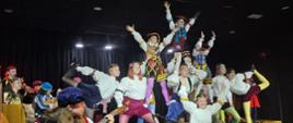 Des enfants en costumes bretons dansent et jouent de divers instruments sur scène.