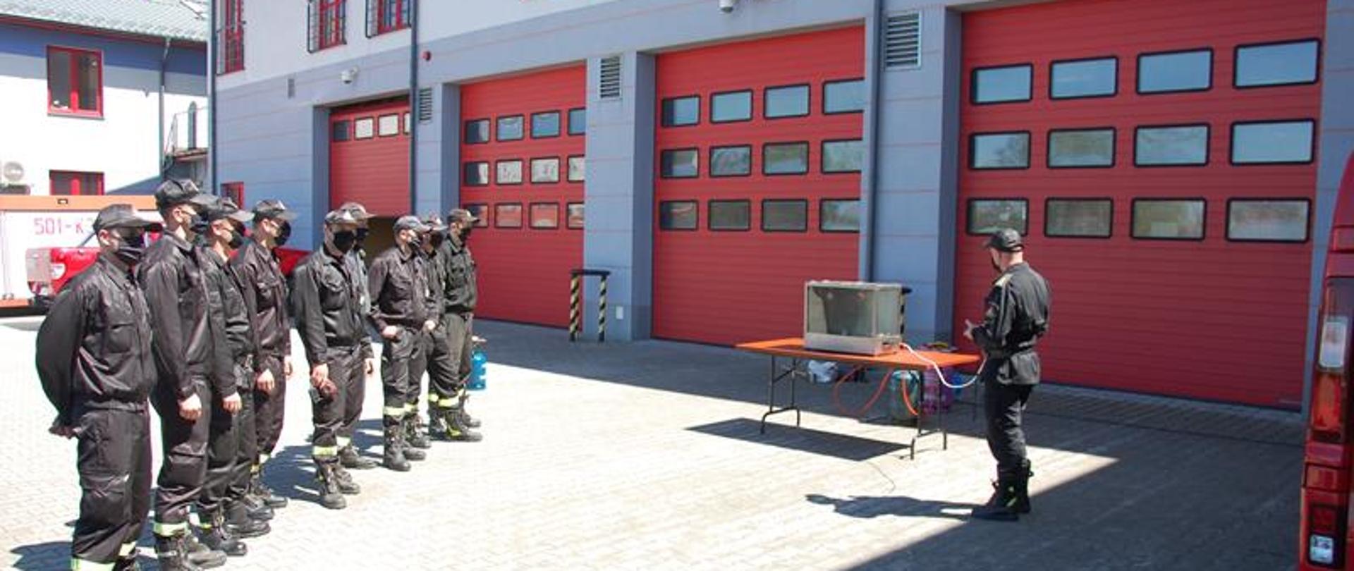 Uczestnicy szkolenia obserwują tworzenie się mieszaniny wybuchowej w "Akwarium Giselssona”.Zajęcia odbywają się na placu wewnętrznym Komendy Powiatowej