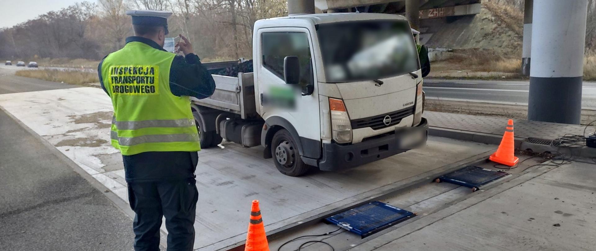 Samochód dostawczy stoi przez wagą. Obok stoi inspektor ITD