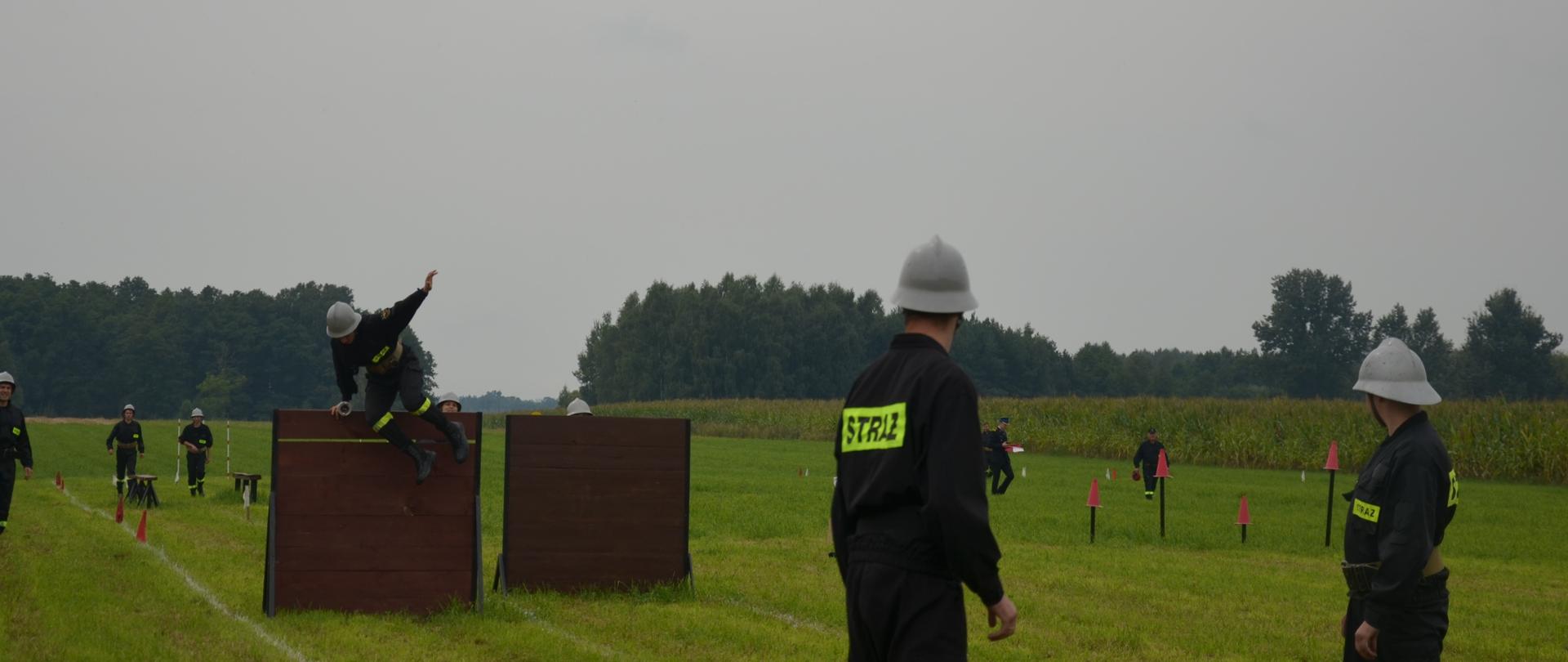 Strażacy OSP w trakcie biegu w konkurencji 7x50m z przeszkodami Gminnych zawodów Sportowo-Pożarniczych w Holonkach.