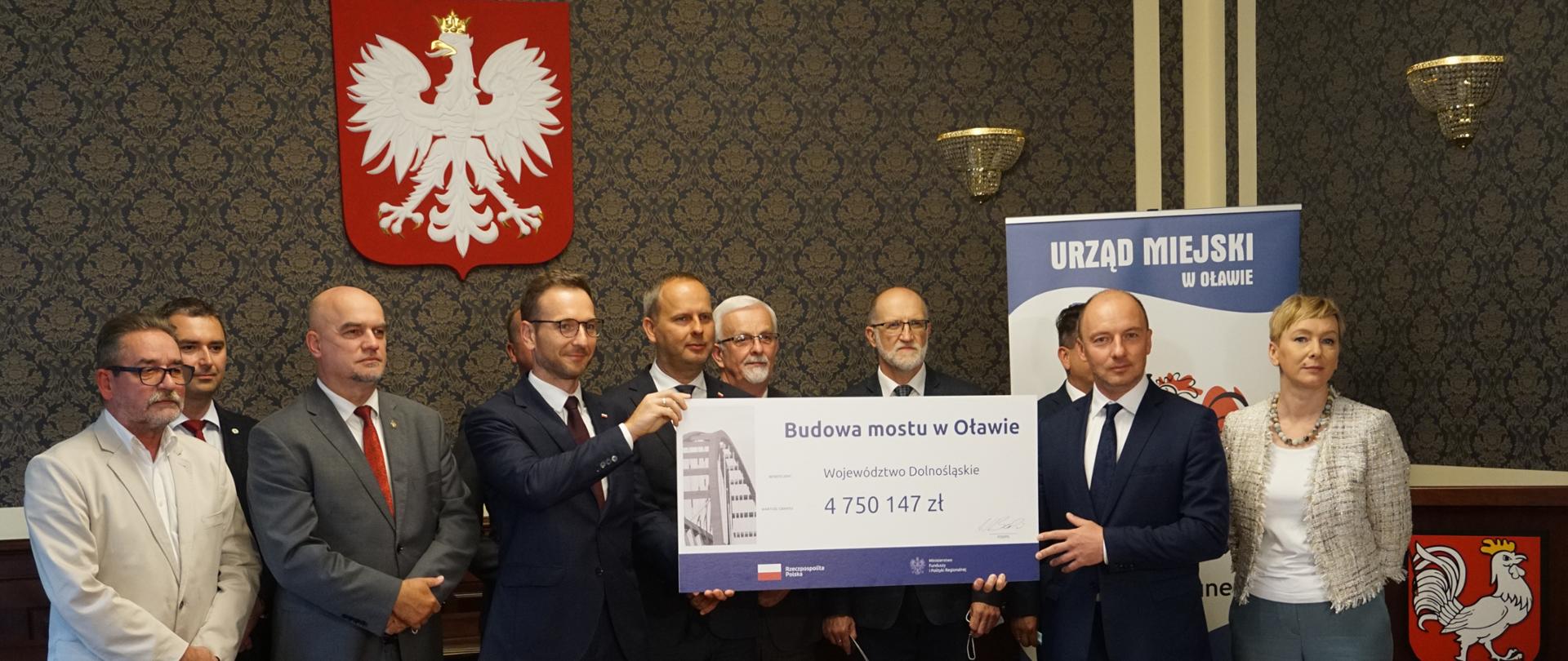 Minister Buda z grupą samorządowców trzyma czek na wysokość 5 milionów złotych 