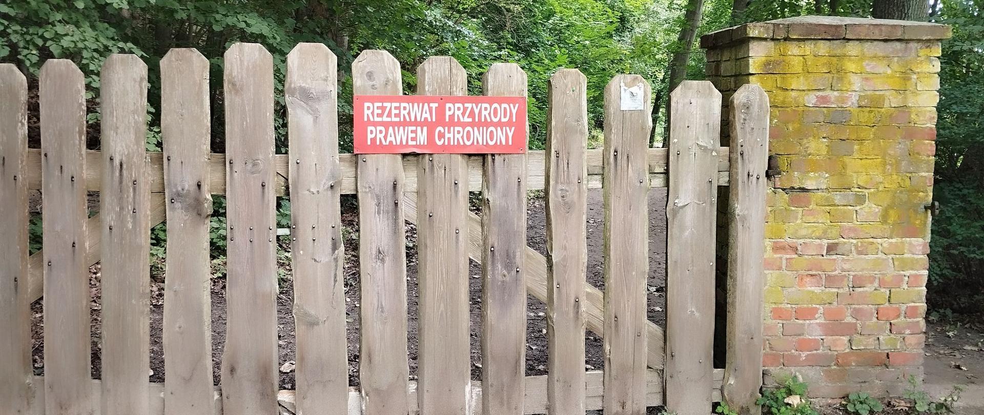 Drewniana brama z napisem: Rezerwat Przyrody Prawem Chroniony