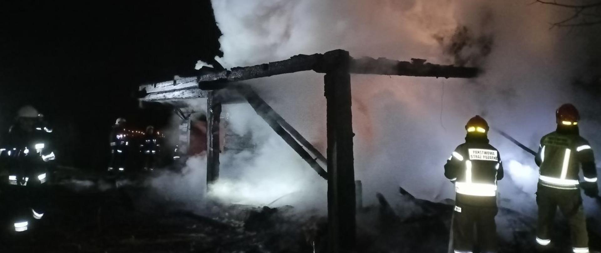 Strażacy gaszą pożar, z którego wydobywają się gęste dymy.