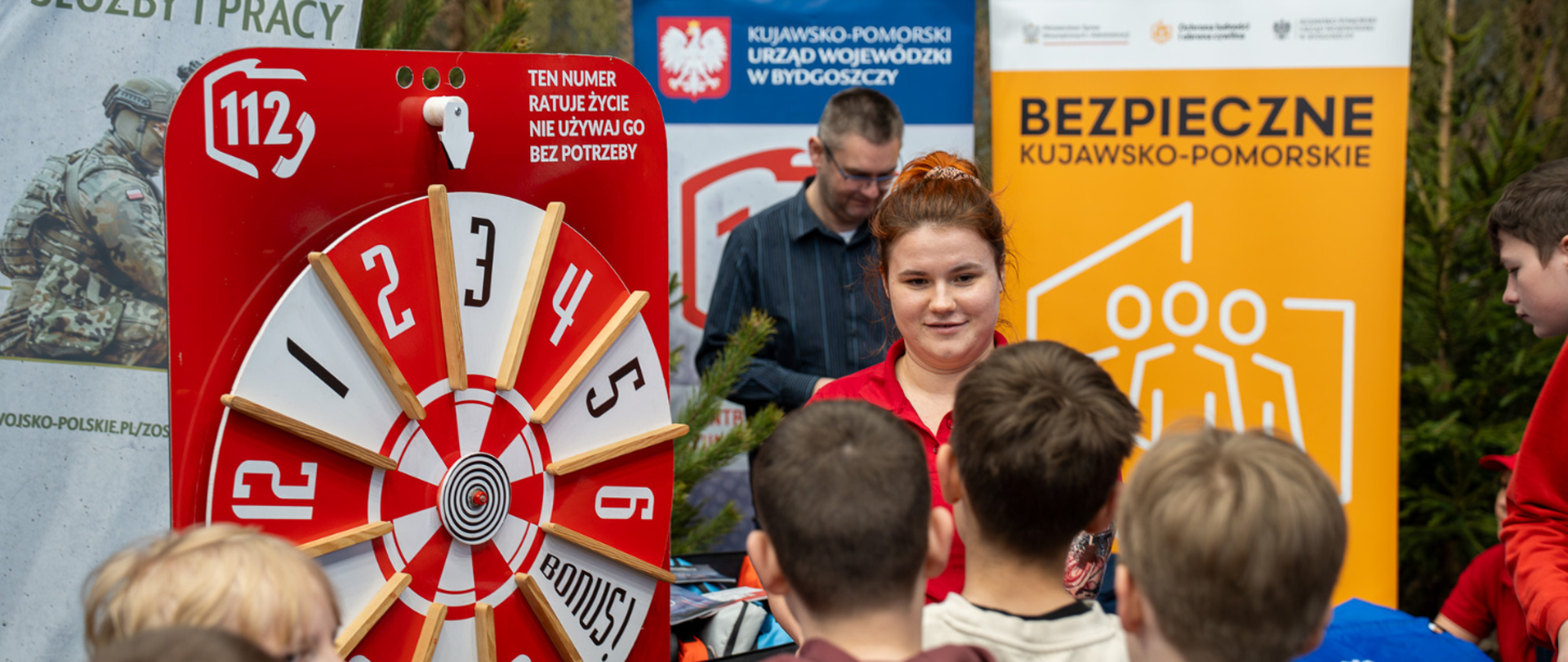 Stoisko Centrum Powiadamiania Ratunkowego w Bydgoszczy, gdzie młodzi uczestnicy biorą udział w zabawie "Koło fortuny"