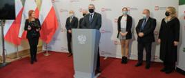 Przemawia wiceminister Wojciech Murdzek, za nim stoją pozostali uczestnicy konferencji, za nimi stoi ściana z napisem Ministerstwo Edukacji i Nauki oraz flagi Polski.
