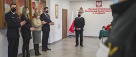 Na sali konferencyjnej podczas uroczystej zbiórki strażacy z Państwowej Straży Pożarnej w mundurach wyjściowych pomiędzy strażakami stoją w ubraniach cywilnych Pani Poseł, Pani Z-ca Kierownika Krus w Gorlicach i Burmistrz Gorlic.