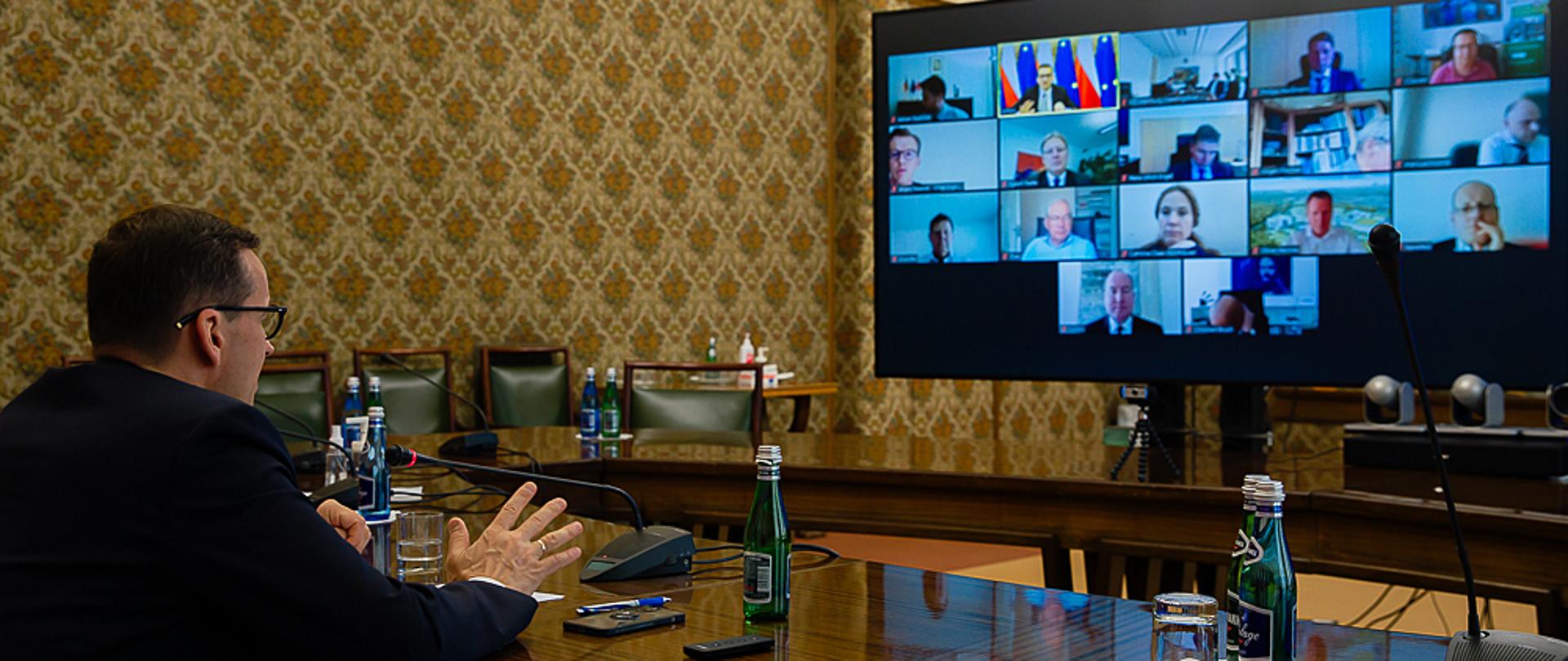 Widok na premiera Mateusza Morawieckiego i ekran z trwającą wideokonferencją.