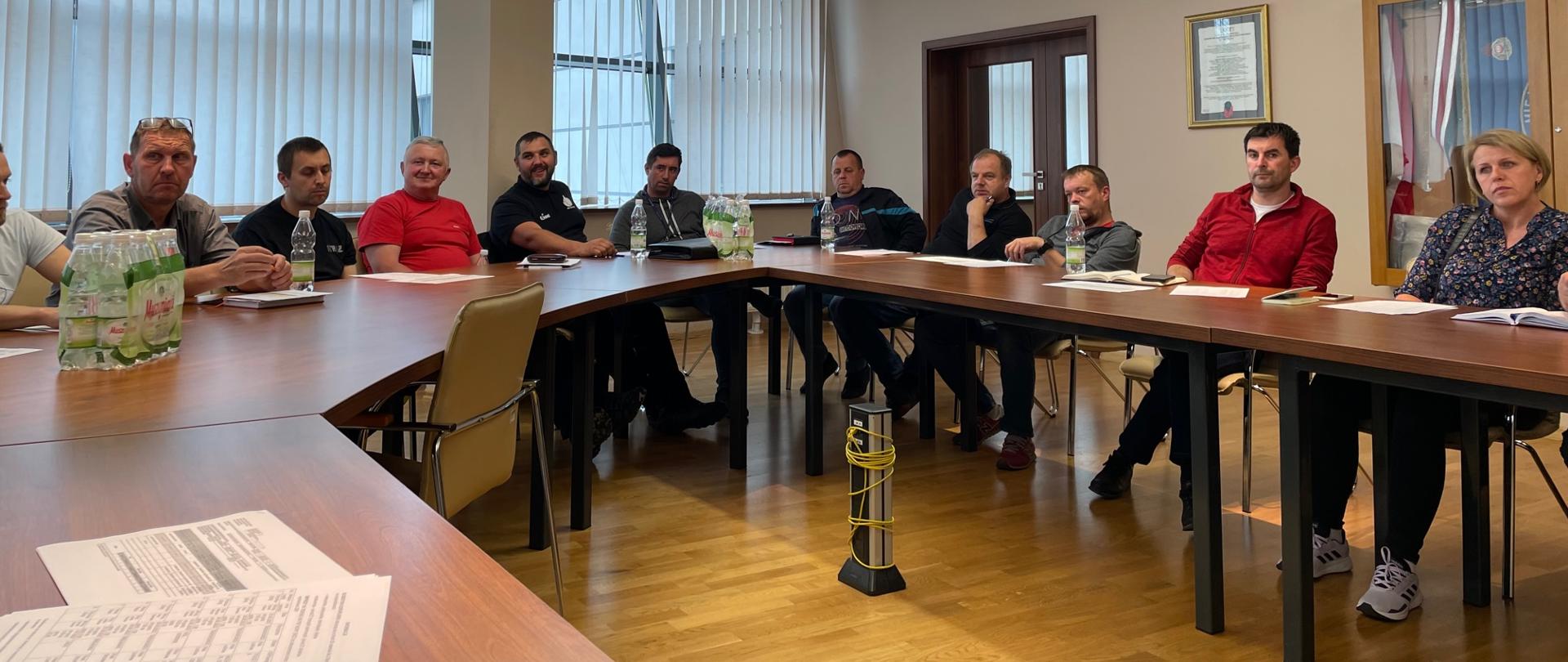 Strażacy podczas odprawy siedzą przy stołach