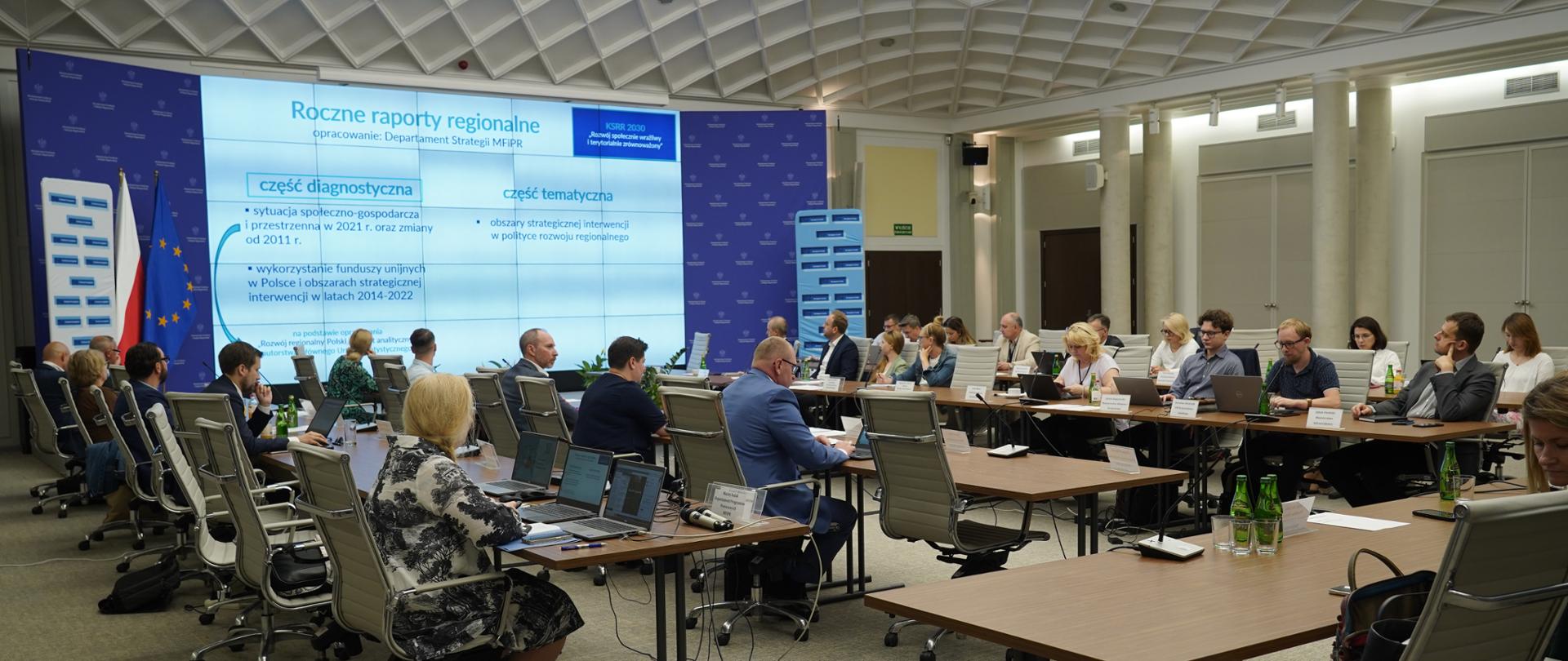 Grupa osób siedzi przy stołach podczas posiedzenia podkomitetu. Na stołach stoją laptopy i mikrofony. 