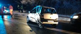 Uszkodzony samochód osobowy Toytoa Yaris na drodze krajowej nr 42 w tle policjanci i służby drogowe