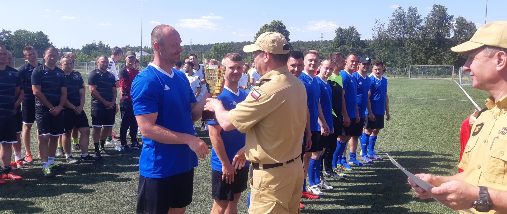 sportowcy na boisku do piłki nożnej podczas wręczania pucharu za zdobycie 3 miejsca w mistrzostwach