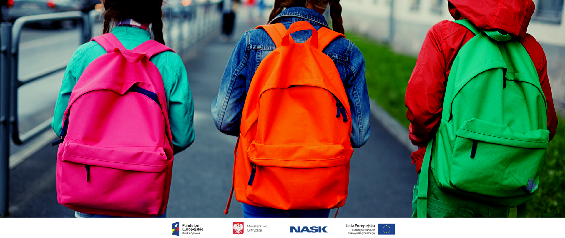 Troje dzieci idzie do szkoły. Mają na plecach kolorowe plecaki. 