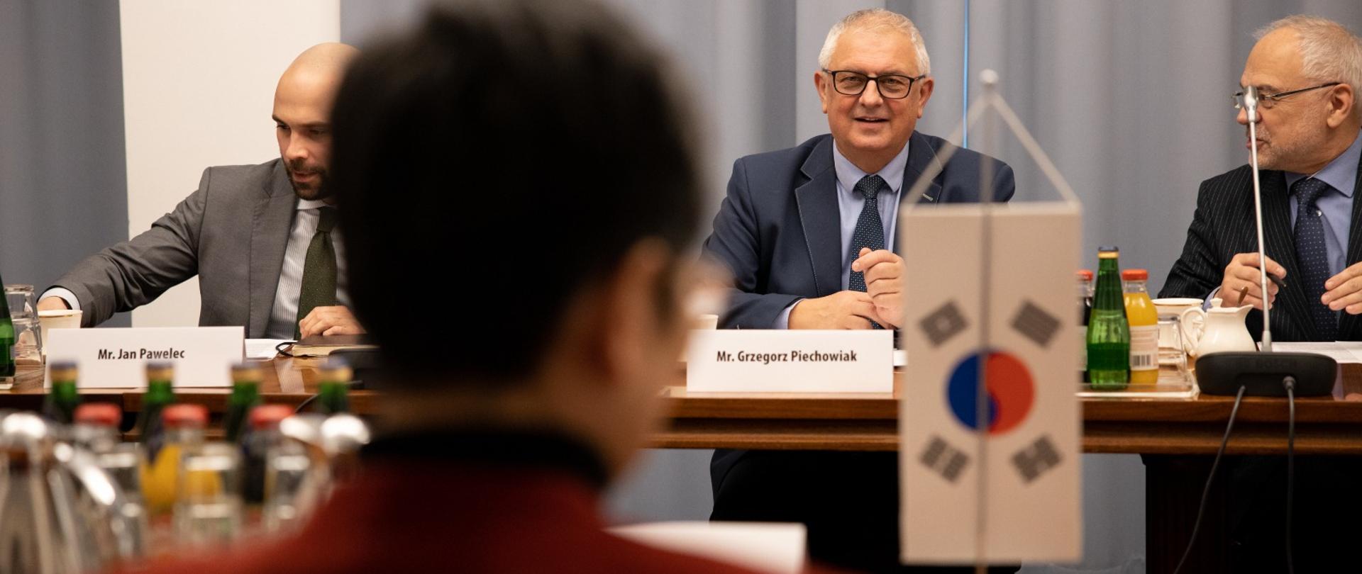 Wiceminister Grzegorz Piechowiak siedzi przy stoli i patrzy na ambasador Korei Południowej w Polsce. Rozmowa dotyczy współpracy gospodarczej obu państw. 