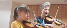 Dziewczynka i kobieta grają na skrzypcach.