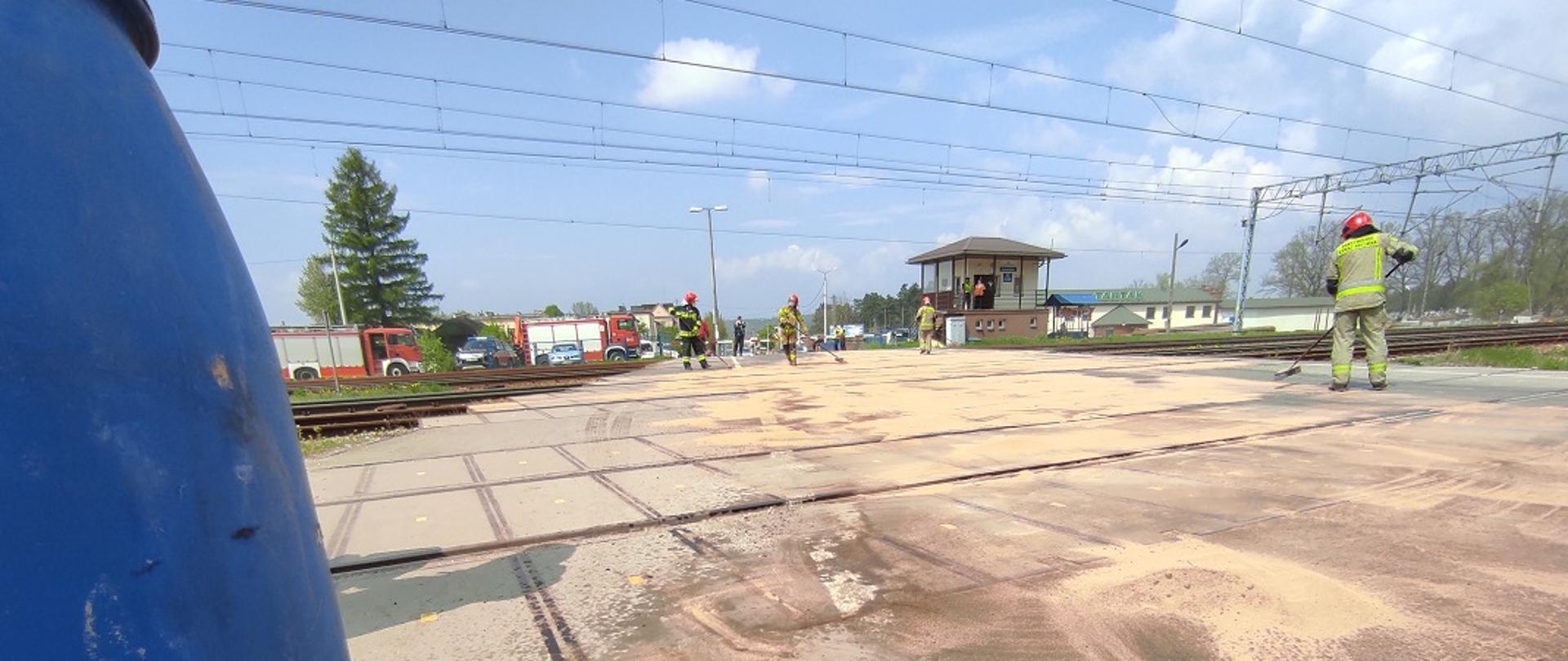 Na zdjęciu widzimy jak strażacy za pomocą sorbentu Compact usuwają rozlany olej hydrauliczny na przejeździe kolejowym zlokalizowanym w miejscowości Suchedniów na ul. Bugaj. Na czas prowadzenia działań przez strażaków ruch kolejowy w miejscu akcji został całkowicie zatrzymany.