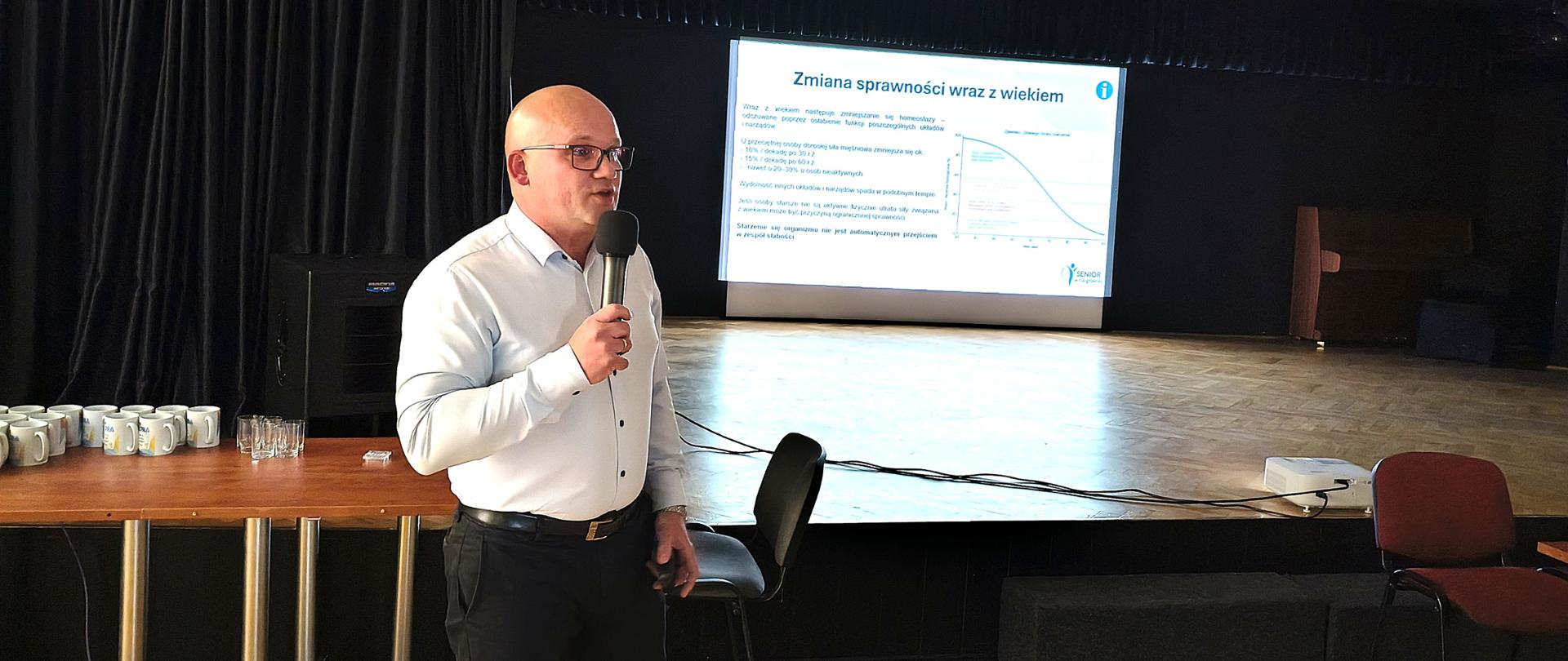 prelegent na tle prezentacji programu "Senior w roli głównej"