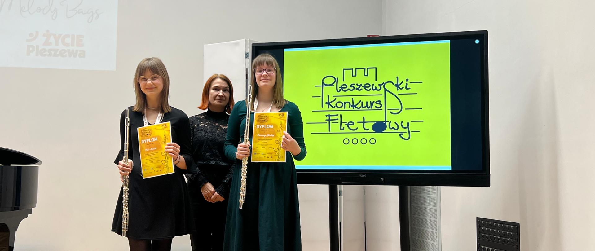 Uczennice ZPSM i nauczycielka na tle banera "Pleszewski Konkurs Fletowy"
