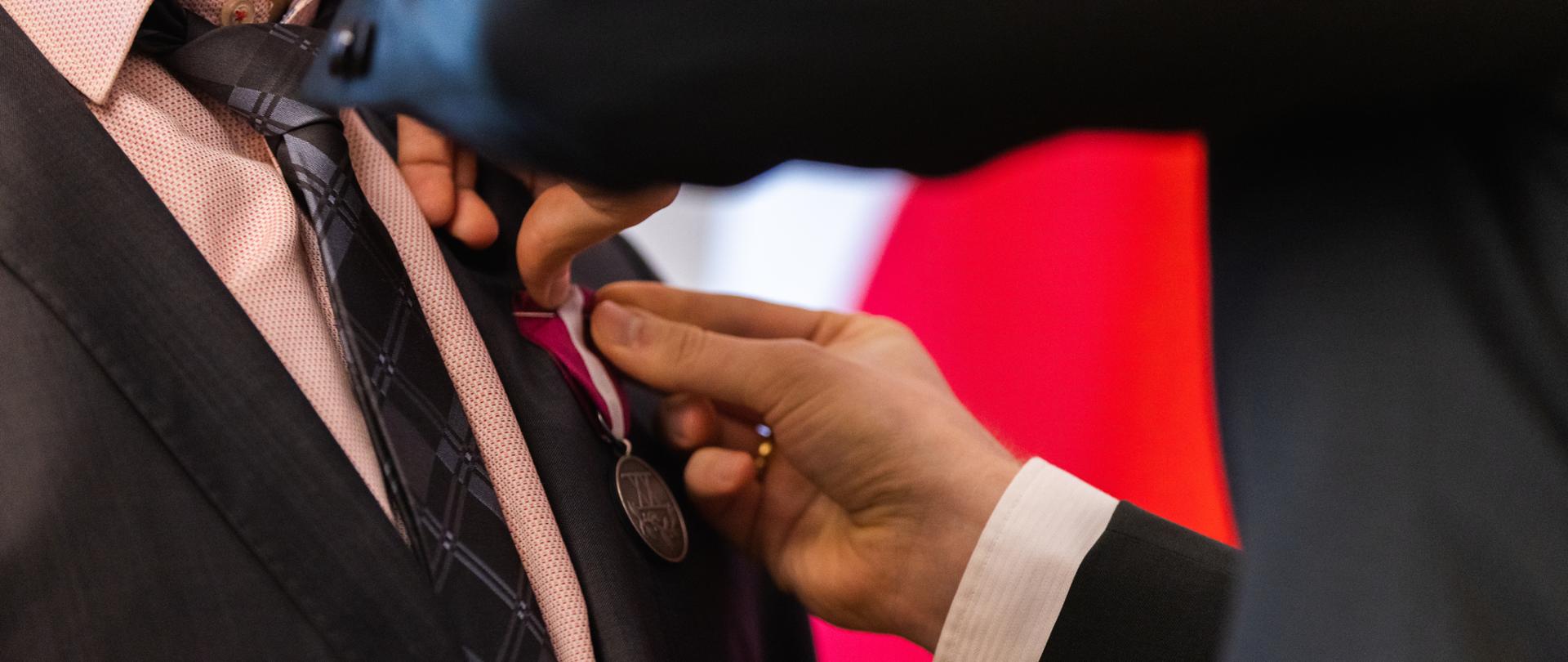 zbliżenie na rękę wicewojewody przypinającą odznaczenie