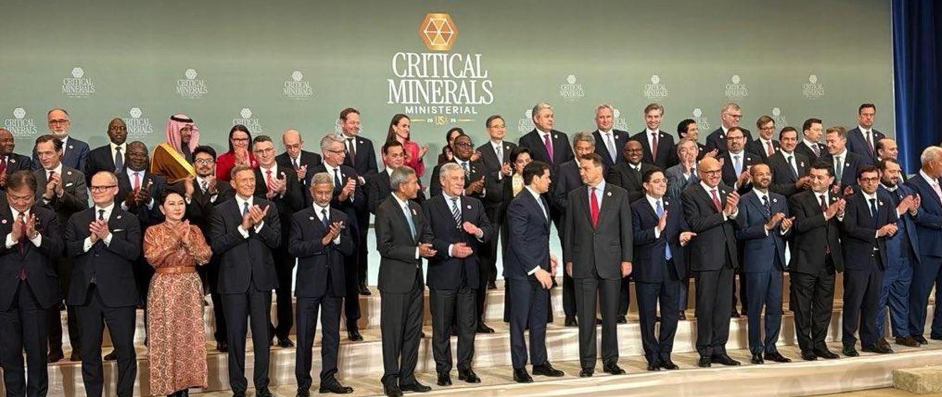 Polish Deputy Prime Minister and Minister of Foreign Affairs Radosław Sikorski standing among government representatives during an official meeting in the United States, with conference signage visible in the background.