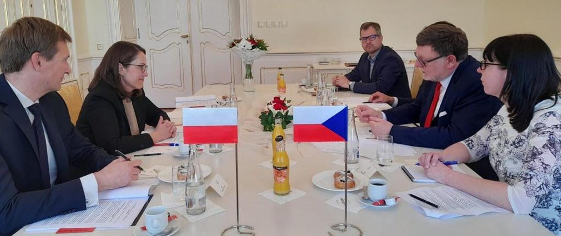 Minister Magdalena Rzeczkowska podczas spotkania z delegacją czeską, przy stole, z filiżankami i flagami Polski i Czech