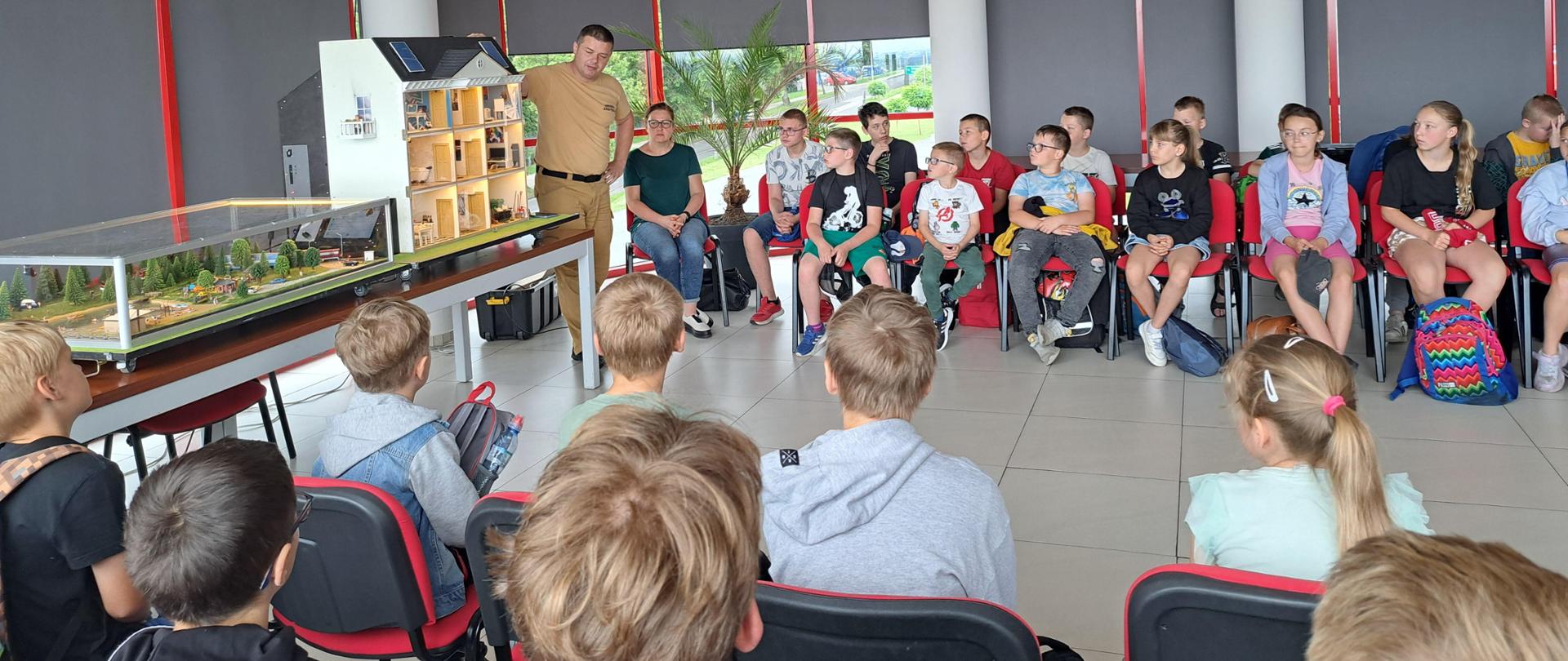 Mobilny symulator pożarów i Gogle VR. Na zdjęciu znajdują się funkcjonariusze komendy oraz dzieci i młodzież podczas prezentacji na sali sztabowej komendy