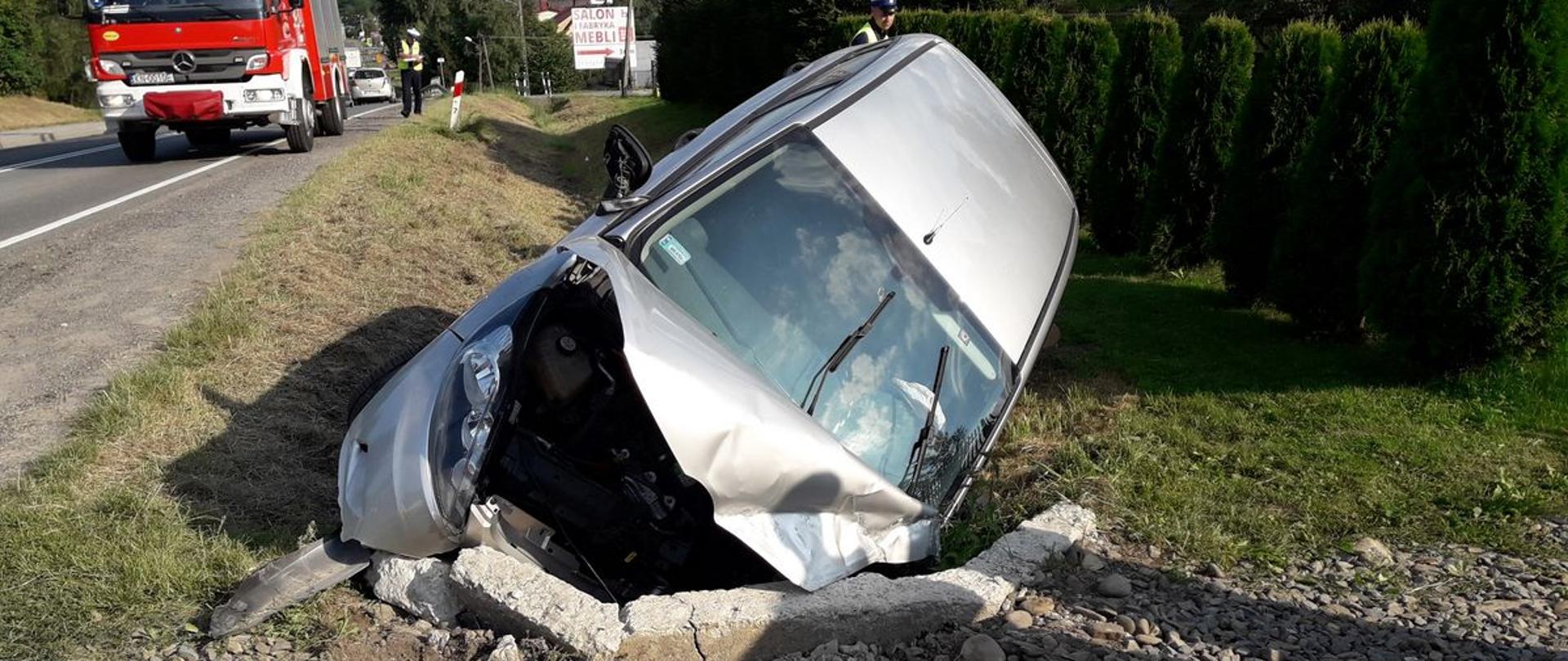Samochód osobowy w rowie przy przepuście a w tle samochód pożarniczy.