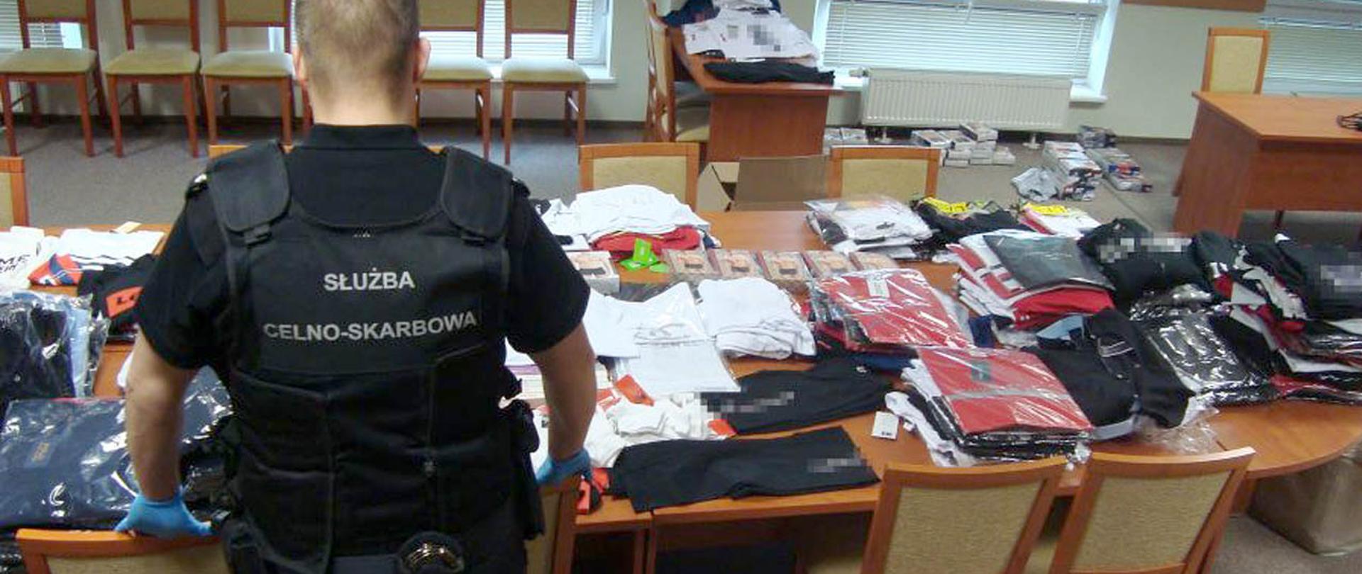 Z lewej strony funkcjonariusz Służby Celno-Skarbowej przy podrobionej odzieży.