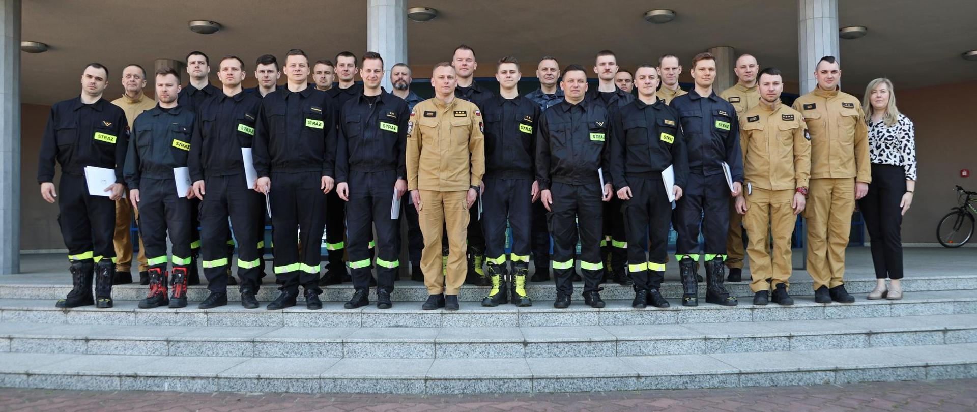 Pamiątkowe zdjęcie grupowe funkcjonariuszy PSP będących uczestnikami szkolenia specjalistycznego w zakresie przeciwdziałania zagrożeniom chemicznym, biologicznym, radiologicznym, nuklearnym i wybuchowym (20 osób)w towarzystwie Zastępcy Komendanta Centralnej Szkoły PSP, kobiety oraz trzech funkcjonariuszy CS PSP