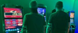 Dwóch funkcjonariuszy stoi przy automatach do gier