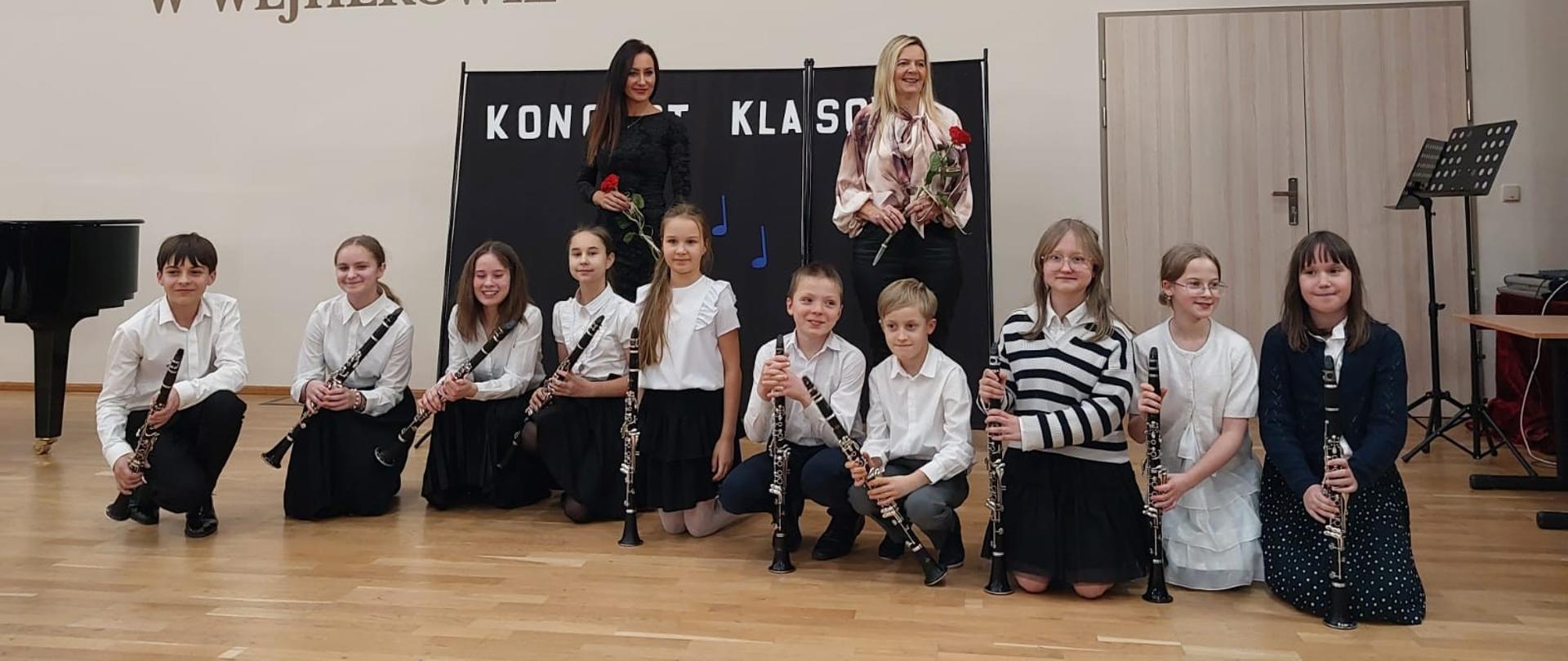 Na sali koncertowej pozują z klarnetami uczniowie oraz nauczycielki Anna Łysko i Urszula Zakrzewska