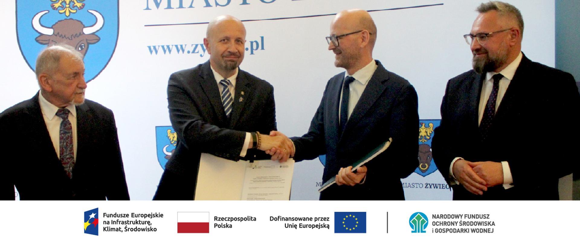 Zdjęcie grupowe. W stopce grafiki ciąg logotypów: Fundusze Europejskie na Infrastrukturę, Klimat, Środowisko, flaga Rzeczypospolita Polska, flaga UE i Dofinansowane przez UE, NFOŚiGW.