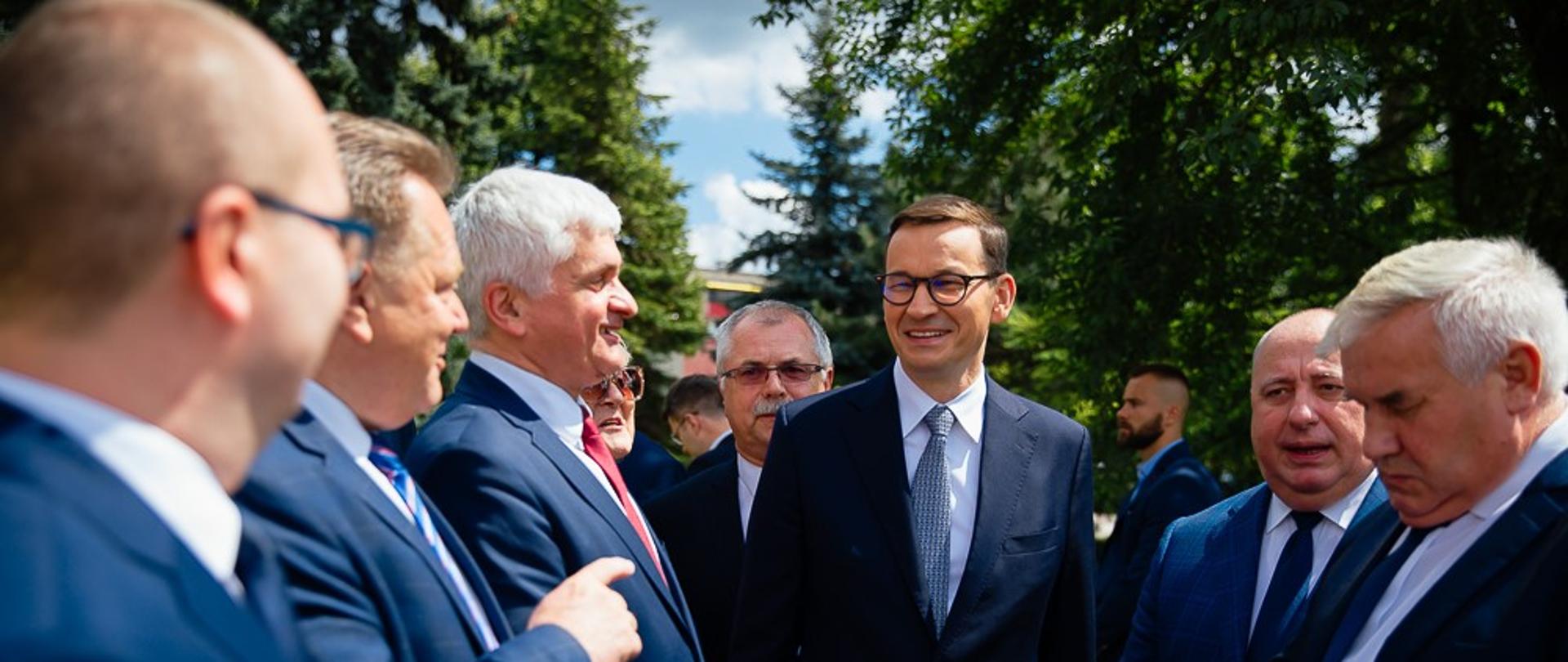 Premier Mateusz Morawiecki idzie po drodze w towarzystwie.