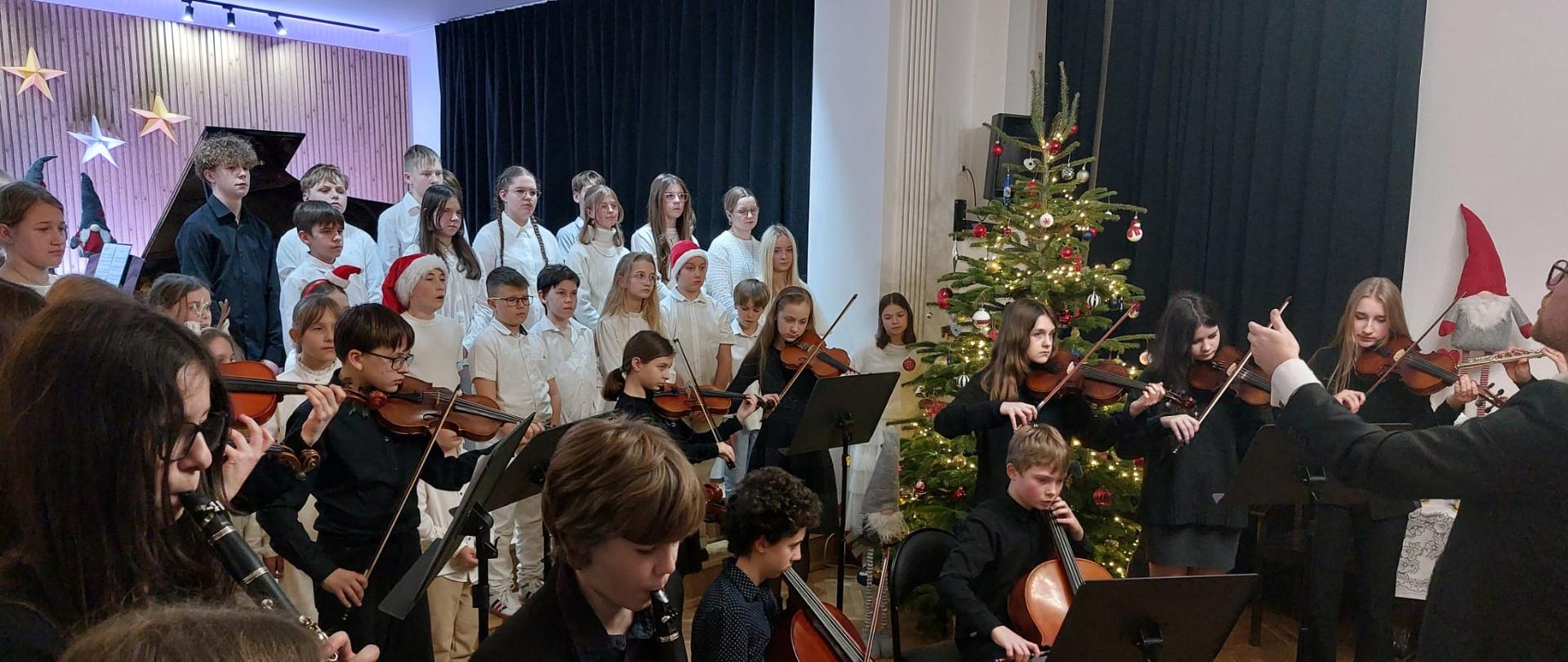 Galeria 26 zdjęć - uczniowie odświętnie ubrani grają na instrumentach kolędy i pastorałki - 17.12.2025