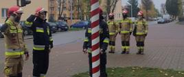 Siedmiu strażaków podczas podnoszenia flagi państwowej przed budynkiem Komendy Straży