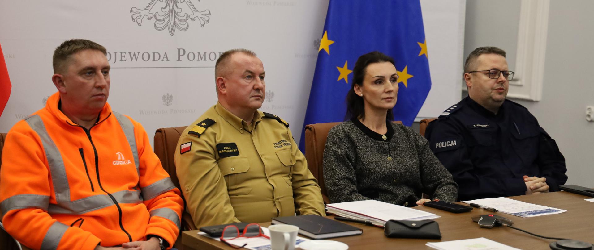 wideokonferencja z premierem kraju. cztery osoby, w tym dwóch mundurowych siedza za stołem i patrzą na ekran
