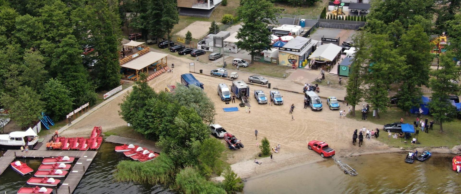Widok z lotu ptaka na plaże, gdzie stoją samochody służbowe.