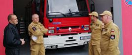 Strażacy przed garażem OSP w tle samochód gaśniczy