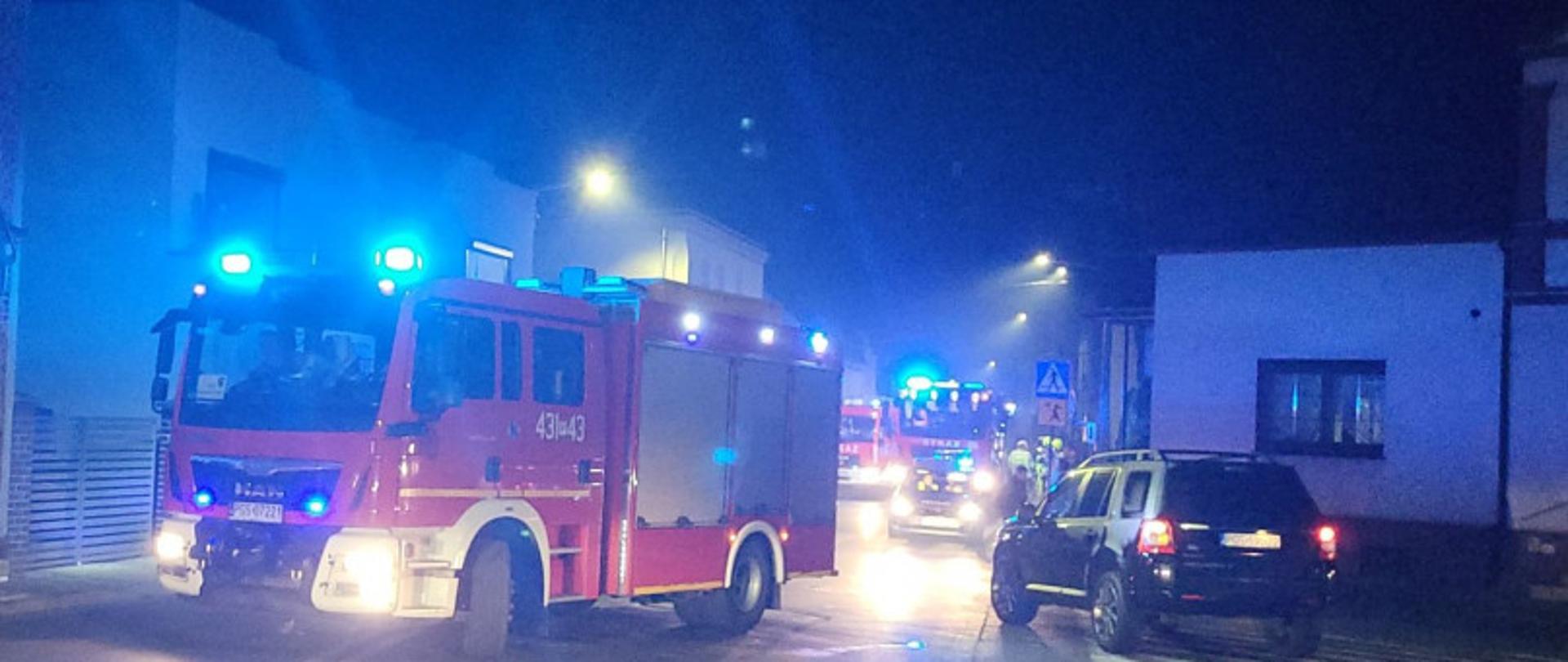 Samochód pożarniczy stoi na drodze podczas interwencji.