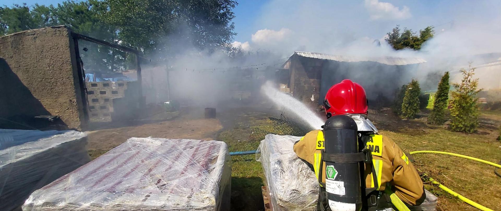 Widać strażaka, który gasi pożar wiaty