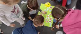 dzieci układają obrazki ze zdrowymi przekąskami na zielonej planszy
