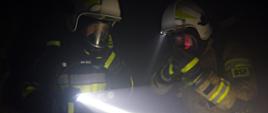 Dwaj strażacy OSP w ciemnej piwnicy w aparatach OUO.