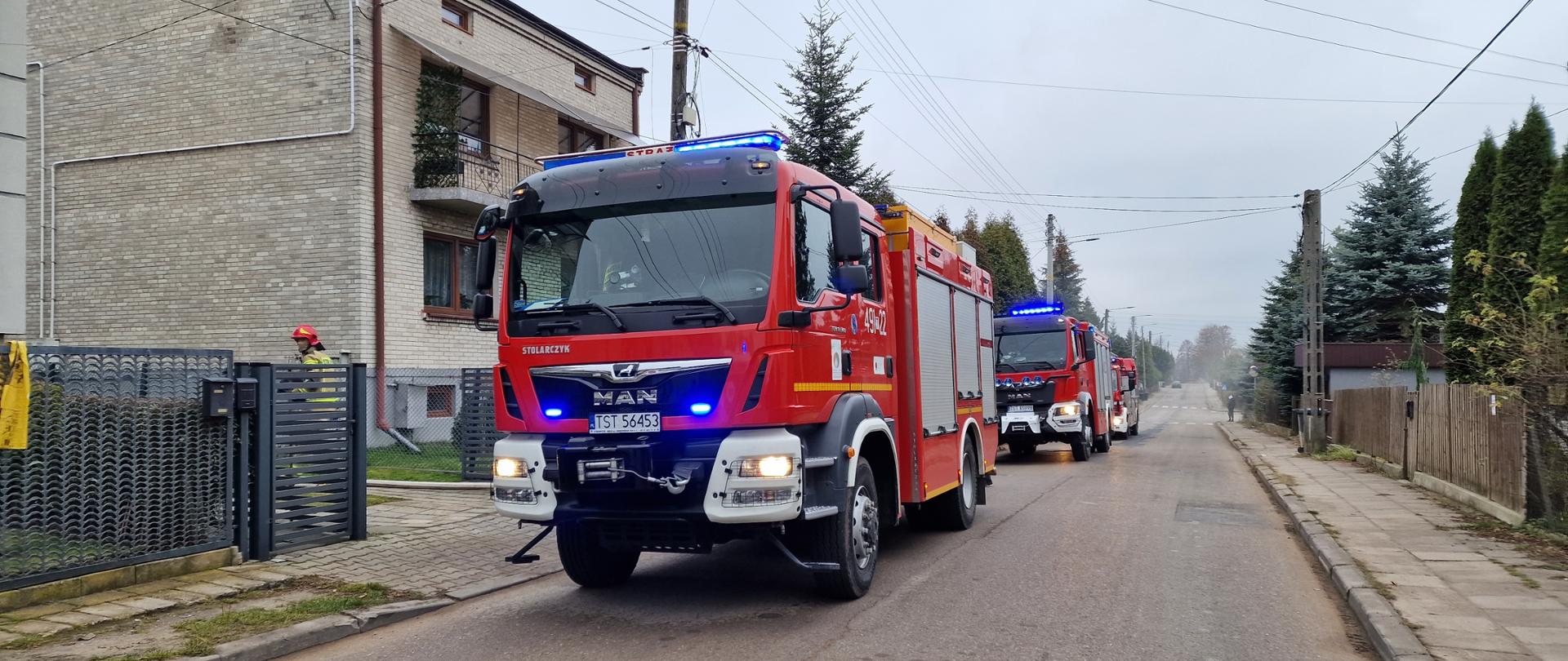 Pojazdy pożarnicze na ulicy przed budynkiem jednorodzinnym