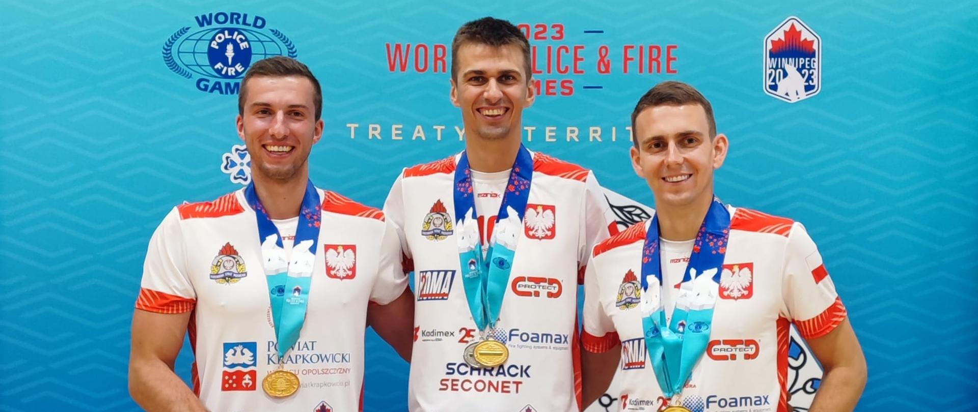 Trzech strażaków w strojach sportowych z medalami