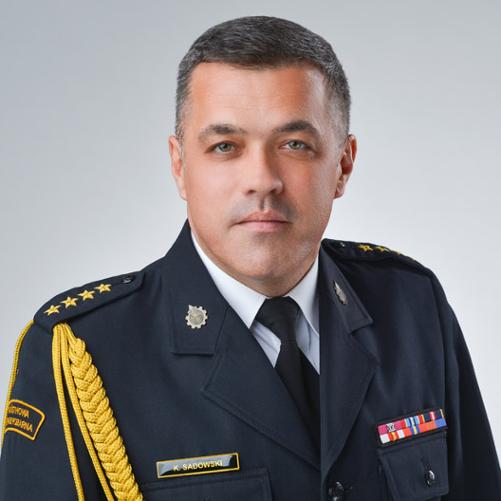 Na zdjęciu znajduje się Zastępca Komendanta Powiatowego PSP w Będzinie ubrany w mundur wyjściowy wraz ze sznurem.