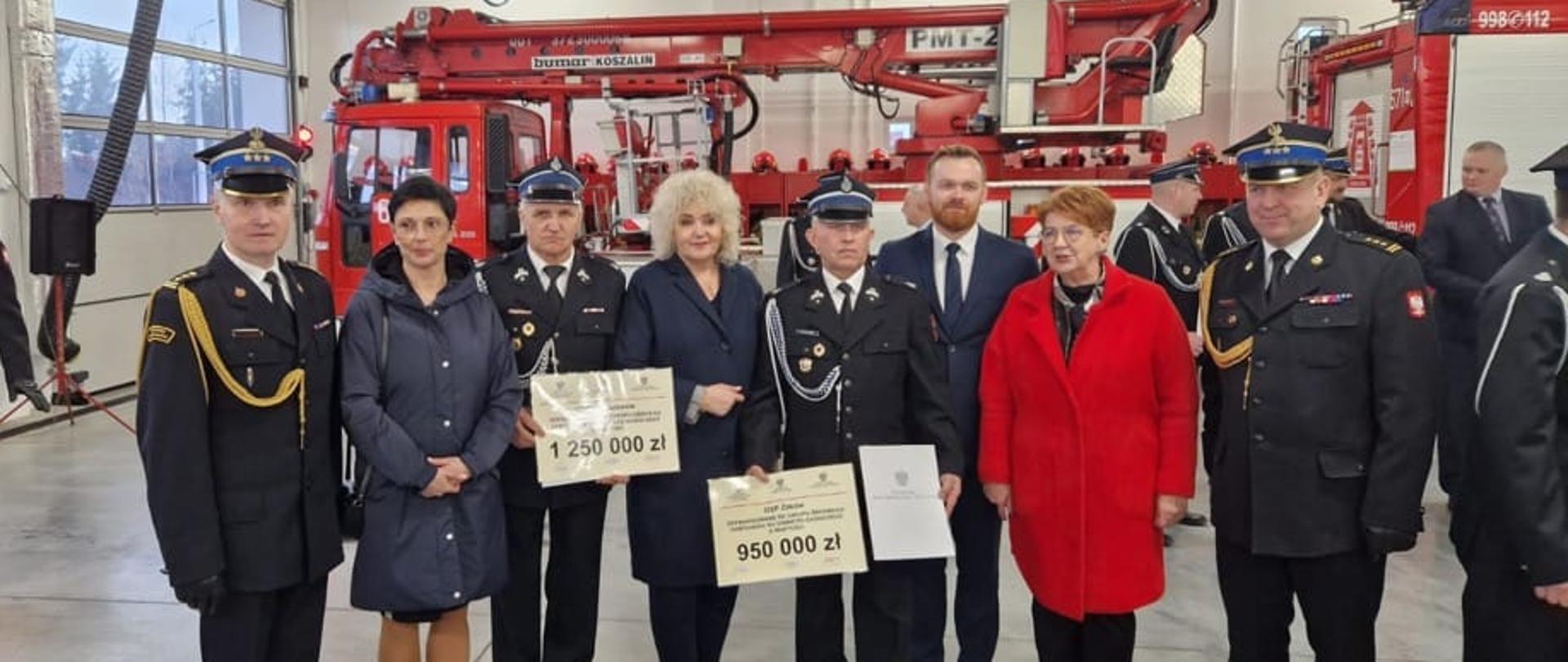 Zastępca Mazowieckiego Komendanta Wojewódzkiego PSP, Komendant Powiatowy, wójtowie, parlamentarzyści oraz członkowie OSP na zdjęciu grupowym z promesami na tle samochodów ratowniczo-gaśniczych