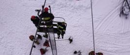 Zdjęcie przedstawia strażaków podczas ćwiczeń z ewakuacji osób z kolei linowej.