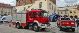 Samochód gaśniczy i pojazd rozpoznania ratowniczego Komendy Miejskiej PSP w Tarnowie ustawione na rynku w czasie wydarzenia „Lato z Radiem i Telewizją Polską”. W tle renesansowy ratusz i stoisko TVP.